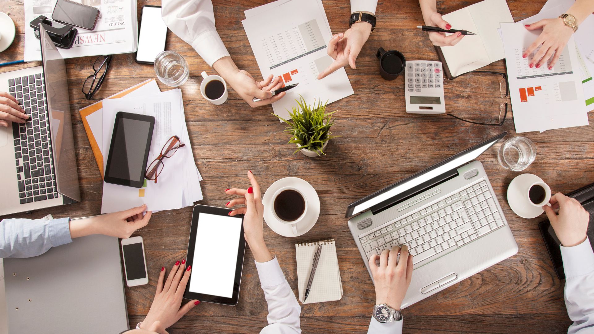 ホットペッパービューティー運用代行 - プロフェッショナルチームによる戦略的コンサルティング Growth Partners Japanのプロフェッショナルチームによるホットペッパービューティー運用コンサルティングの様子。木製テーブルを囲んでノートパソコン、タブレット、資料を使いながら戦略を練る専門家たち